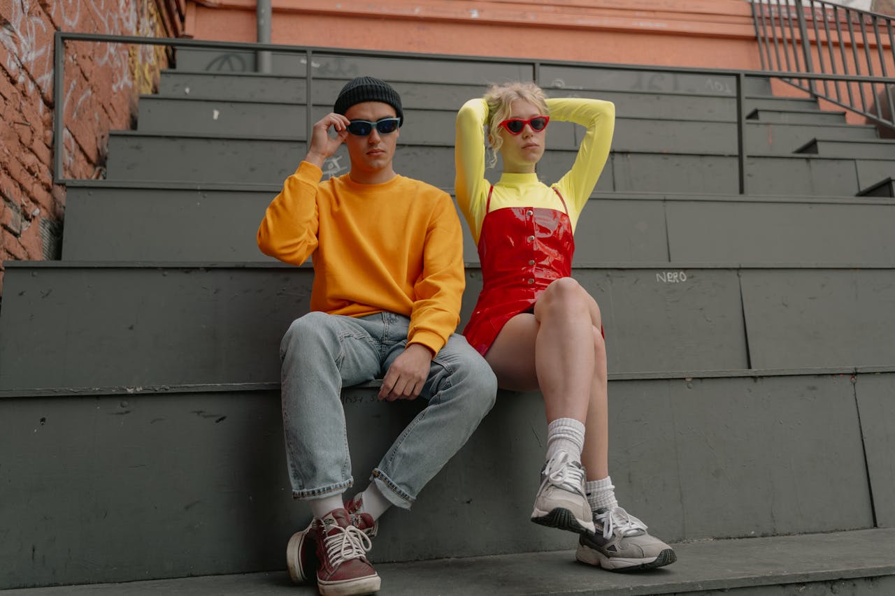 about-01 Trendy young adults in vibrant outfits and sunglasses sitting on industrial bleachers.
